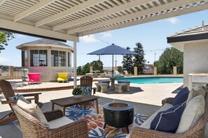A covered outdoor area with a pool, seating, and a gazebo.
