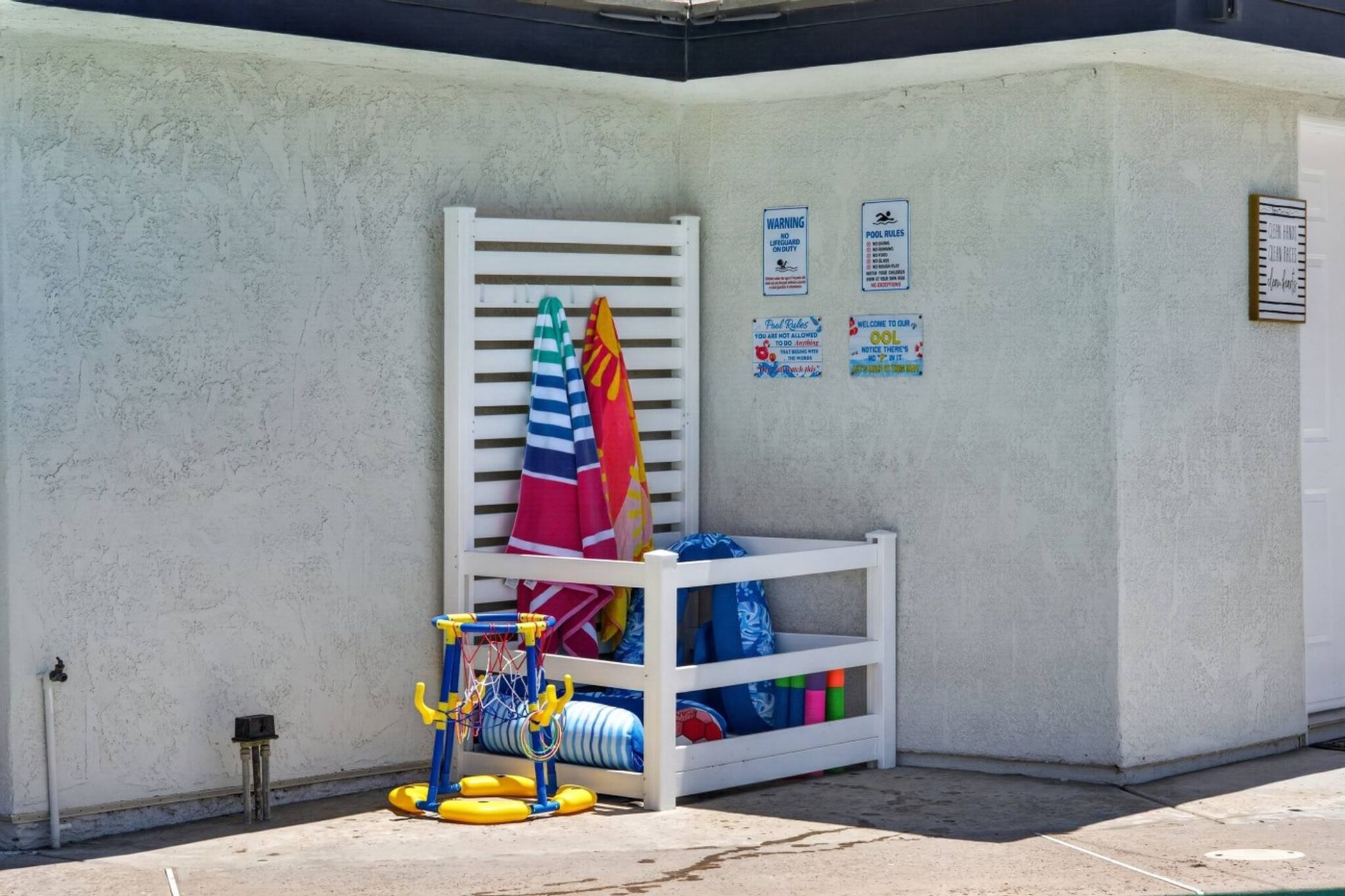A poolside area with a white pool ladder, a children's play structure, and various pool accessories.