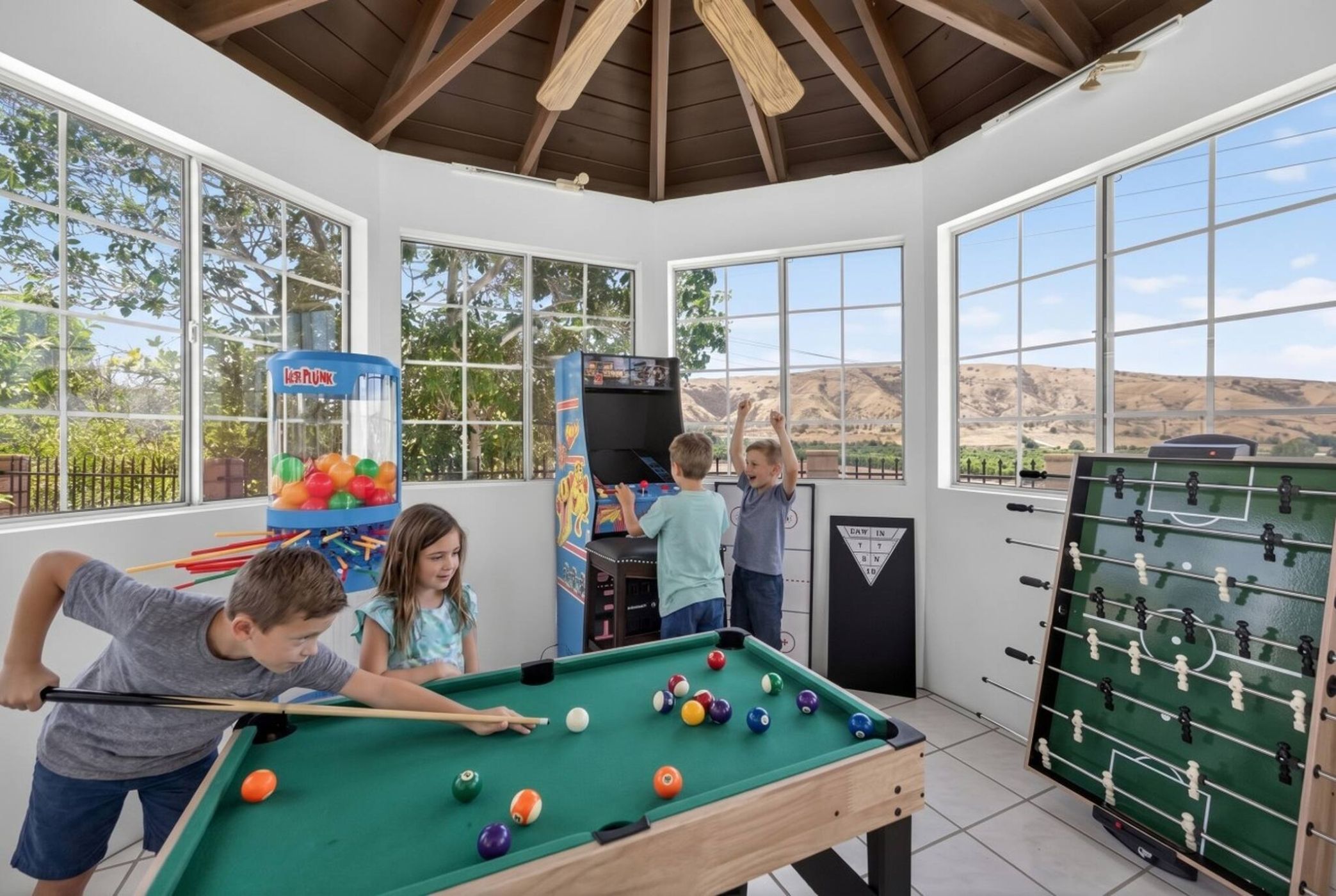 A recreational room with a pool table, foosball table, and a claw machine.
