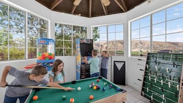 A recreational room with a pool table, foosball table, and a claw machine.
