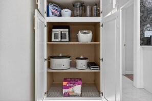A kitchen cabinet with various appliances and a box of kitchen towels.