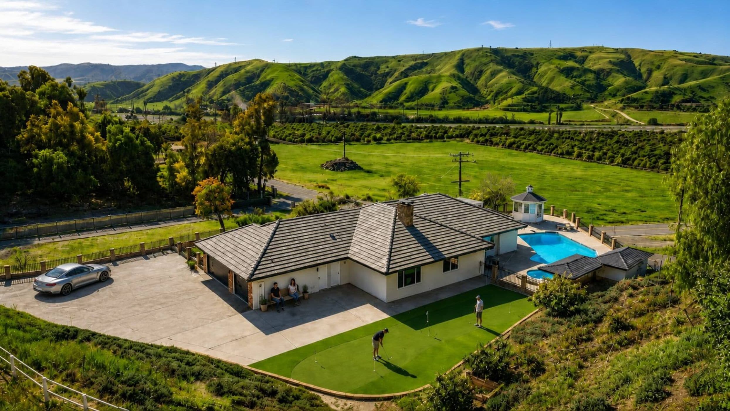 A house with a swimming pool, a tennis court, and a view of green hills.