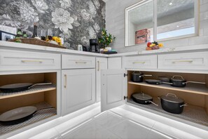 Eine moderne Küche mit weißen Schränken, einer Marmor-Spritzschutzwand und verschiedenen Kochutensilien.