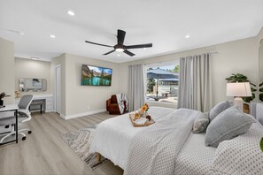 Un dormitorio con cama, escritorio, silla y vistas a una piscina y zona exterior.