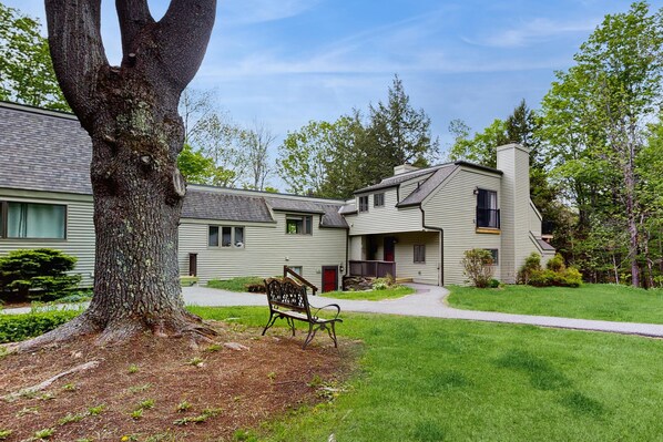A residential building with a large tree, a bench, and a well-maintained lawn. - Kingswood I corner trailside condo at the top of the hill with two big decks (Hartford)