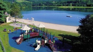 Un'area giochi con uno scivolo e strutture per arrampicarsi vicino a un lago.