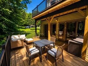 An outdoor deck with a table and chairs, a covered seating area, and a view of the surrounding greenery. - Kingswood I corner trailside condo at the top of the hill with two big decks (Hartford)