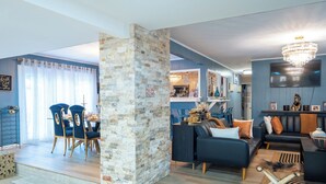 Una sala de estar moderna con comedor, una columna de piedra y una araña.