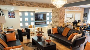 Una sala de estar moderna con chimenea, sofás de cuero y un televisor grande.