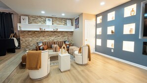 Una sala de estar moderna con una pared de piedra, un conjunto de sofá, una mesa de centro y un televisor montado en la pared.