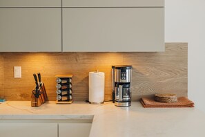 Eine Küchenarbeitsplatte mit Kaffeemaschine, Papierhandtuchhalter, Gewürzregal und Messerblock.