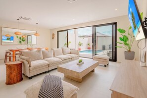 Ein geräumiges Wohnzimmer mit einer großen Couch, einem Couchtisch und einem Essbereich mit Tisch und Stühlen.