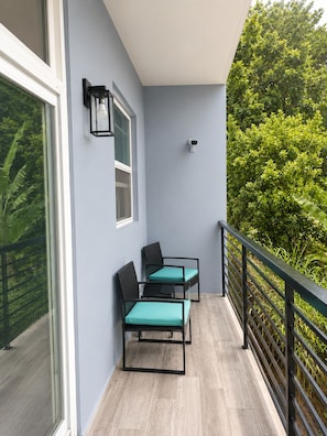 A balcony with two chairs, a window, a wall-mounted light, and a security camera. - Your Caribbean Escape – Lovely 2-Bedroom Apartment in Cochrane, Dominica (Cochrane)