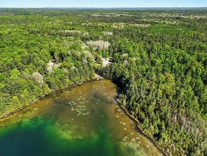 An aerial view of a forested area with a river, clearings, and a small building.
