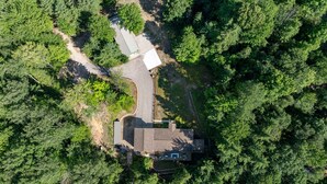 An aerial view of a house surrounded by dense forest, with a clear driveway leading to the entrance. - ✨ Lake Compound | Sauna-Hot Tub-Steam Shower-Cold Plunge (Interlochen)