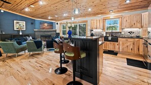 A modern interior with a wooden ceiling, a stone fireplace, a bar area, and a seating area with sofas and chairs. - ✨ Lake Compound | Sauna-Hot Tub-Steam Shower-Cold Plunge (Interlochen)