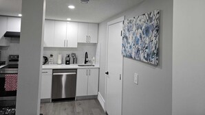 A modern kitchen with white cabinets, a stainless steel dishwasher, and a sink. - Brand New Luxury Basement (Calgary)
