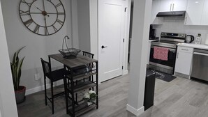 A modern kitchen with white cabinets, a stainless steel oven, and a black countertop. - Brand New Luxury Basement (Calgary)