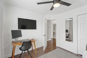 A room with a desk, chair, television, and a ceiling fan. - Charming Midcentury Modern Beltline Home · 3 Mi to Stadium · Sleeps 6 (Atlanta)