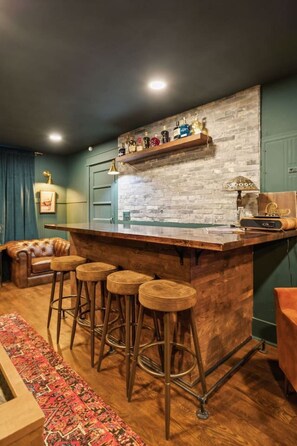 A bar area with stools, a wooden counter, and a brick wall. - Speakeasy. East Nash. Hot tub. Mins to Broadway (Nashville)