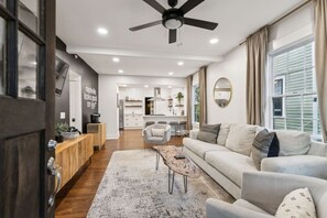 A modern living room with a sofa, coffee table, and a view of the kitchen and dining area. - Speakeasy. East Nash. Hot tub. Mins to Broadway (Nashville)