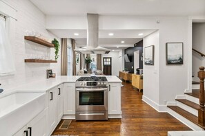 A modern kitchen with white cabinetry, a stainless steel stove, and a wooden island. - Speakeasy. East Nash. Hot tub. Mins to Broadway (Nashville)