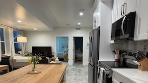 A modern kitchen with white cabinets, a wooden island, and a patterned rug.