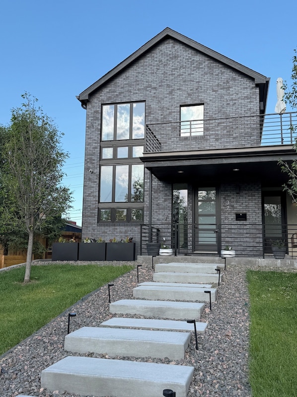 A modern two-story house with a brick exterior, large windows, and a front porch.