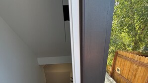 A modern interior with a staircase leading to a second floor, a wooden door, and a potted plant with flowers.