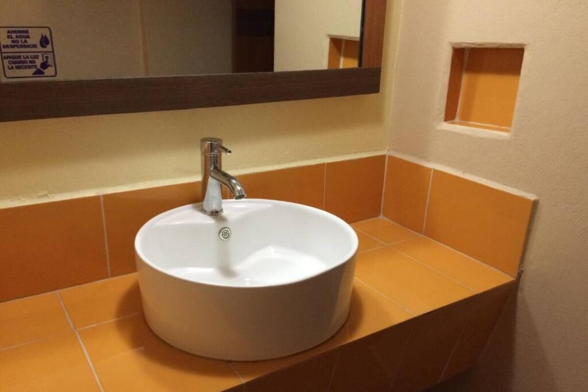 A bathroom sink with a mirror above it, a towel rack, and a sign on the wall.