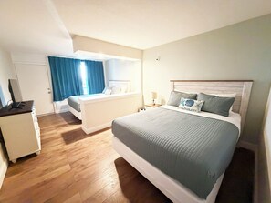 Quarto com duas camas, mesa de cabeceira, abajur e guarda-roupa.
