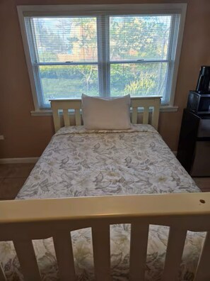 A bedroom with a bed, a window, and a desk.