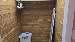 Ein kleines Badezimmer mit Holzwänden, einem Regal, einem Korb und einer Heizung.
