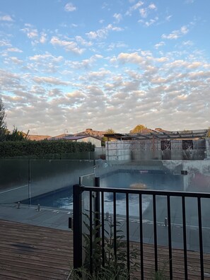 Zona de piscina en la azotea con vista al paisaje urbano y cielo nublado.