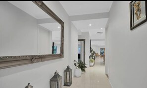 A hallway with a large mirror, potted plants, and a decorative lantern. - 3 bedroom estate 20km from CBD , 30km from both airports 15km Williamstown beach (Truganina)