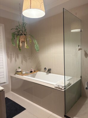 Un baño moderno con cabina de ducha de vidrio, una bañera independiente y una planta colgante.