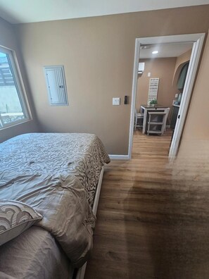Ein Schlafzimmer mit einem Bett, einem kleinen Tisch und einem Stuhl im Hintergrund.