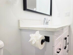 A toilet paper holder with a roll and a bow on a white bathroom counter. - New 2-Bed Suite in SW Edmonton near Windermere & YEG Airport (Edmonton)