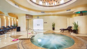 Zona de spa con piscina central, sillones de descanso e iluminación colgante en el techo.