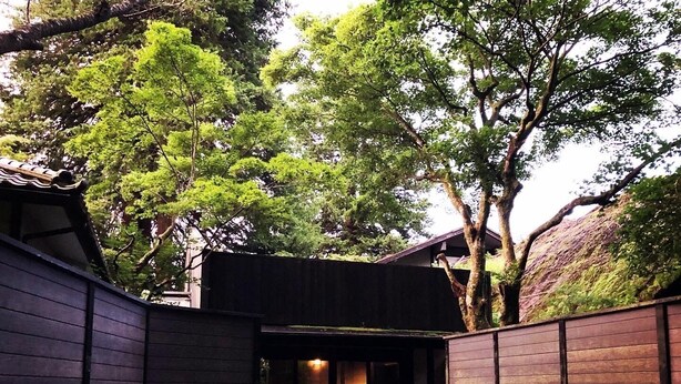 Ein traditionelles japanisches Gebäude mit dunklem Holzfassade, einem Ziegeldach und einem überdachten Eingang.
