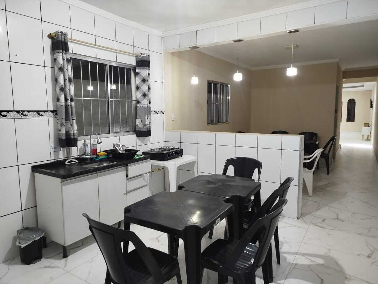 Una cocina compacta con zona de comedor, paredes de azulejos blancos y una ventana pequeña.