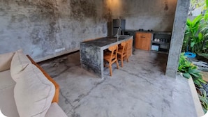 A modern kitchen with a central island, wooden chairs, and a built-in oven. - Villa Segari Canggu  (Canggu)