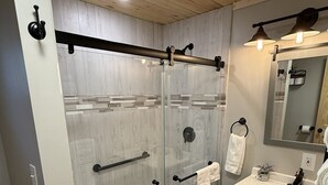 A modern bathroom with a glass-enclosed shower, a vanity with a sink, and a mirror above the sink.