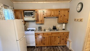 A kitchen with wooden cabinets, a microwave, a stove, and a refrigerator.