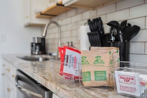 Eine Küchenarbeitsplatte mit Säcken Quaker Oats und Kirkland Produkten, einer Kaffeemaschine sowie Küchenutensilien.