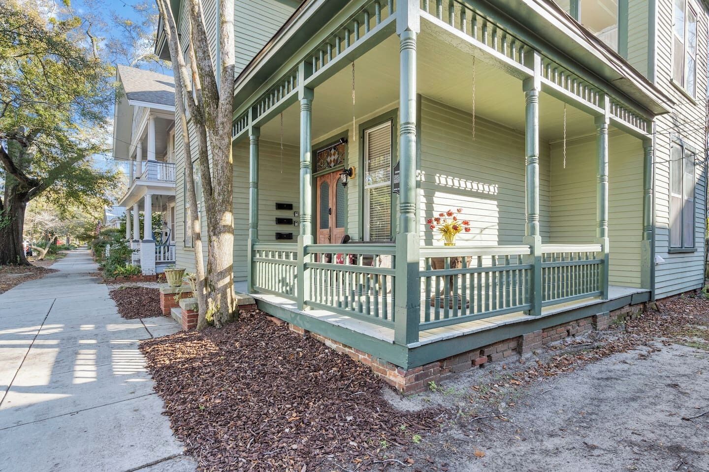 A two-story house with a porch, a front door, and a small garden area.
