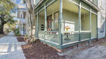 A two-story house with a porch, a front door, and a small garden area.