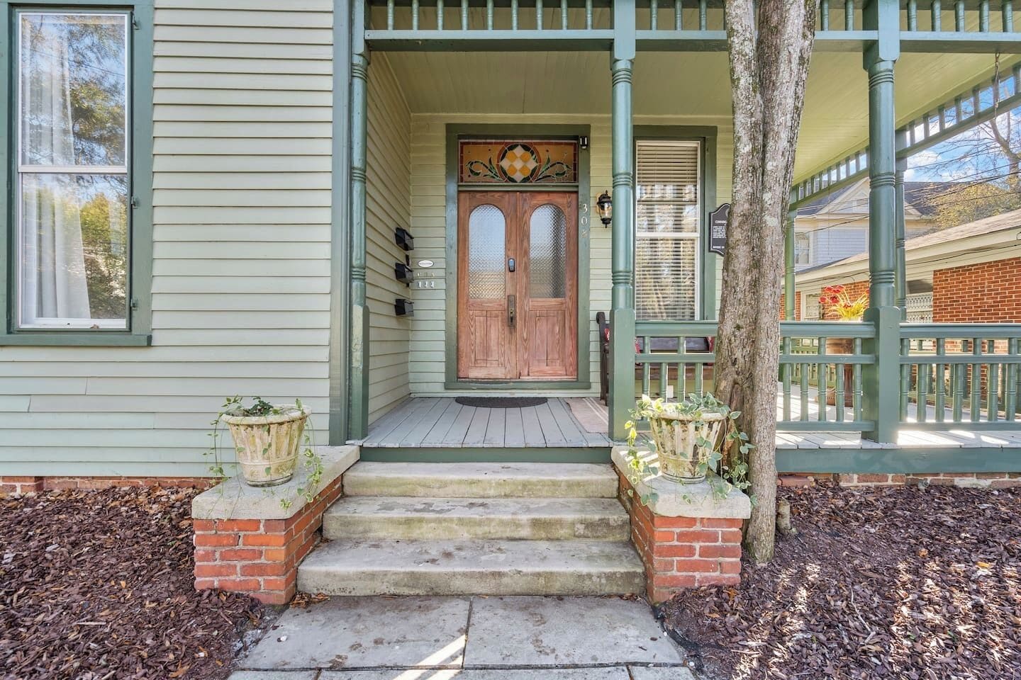 A house with a front porch, a wooden door, and steps leading to the entrance.