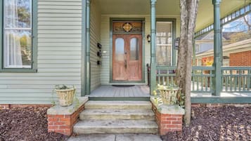 A house with a front porch, a wooden door, and steps leading to the entrance.