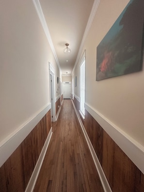 Ein Flur mit Holzboden, weißen Wänden und einem Deckenventilator.